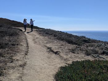 People standing on shore by sea against sky