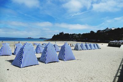 Striped tents at beach against sky