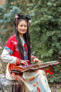 Portrait of smiling young woman standing against trees