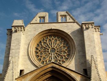 Low angle view of rose window at tarragona cathedral against sky