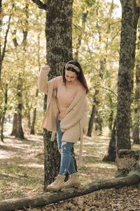 Young woman walking on a wooden log in the middle of a forest