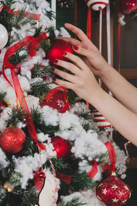 Cropped hands of woman decorating christmas tree at home