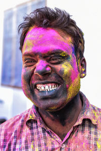 Man clenching teeth with power paint on face during holi