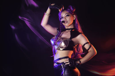 Midsection of woman standing against illuminated lighting equipment