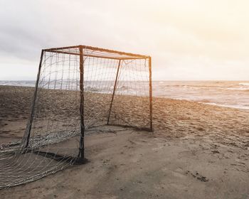 Abandoned net on beach against sky during sunset