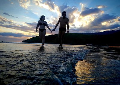 People on beach against sky during sunset