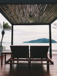 Empty chairs and tables against sky seen through window