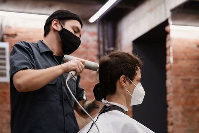 Young man holding camera while standing at home