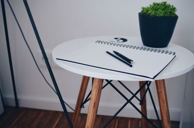 High angle view of pen with pencil and diary by potted plant on table