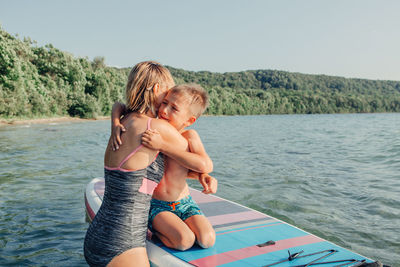 Rear view of shirtless boy and woman in water