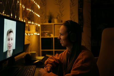 Side view of smiling woman talking on video call at home