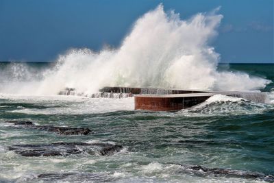 Waves splashing on sea against sky