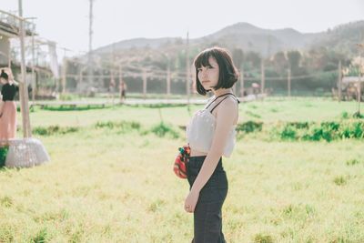 Side view of young woman standing on field