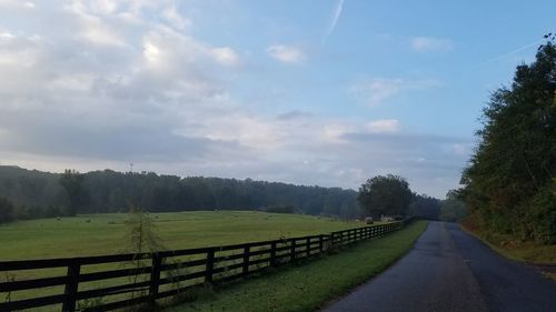 Road amidst field against sky