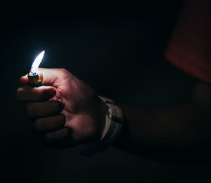 Close-up of hand holding illuminated light over black background