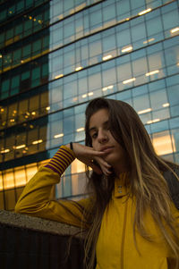 Beautiful young woman standing against illuminated building at night