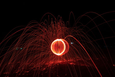 Illuminated wire wool spinning against sky at night