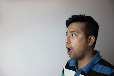 Portrait of young man looking away against white background