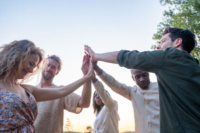 Low angle view of woman with arms raised against sky