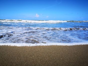 Scenic view of beach against blue sky