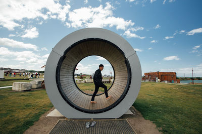 Side view of man walking in circular built structure on land against sky