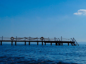 Bridge over sea against clear blue sky