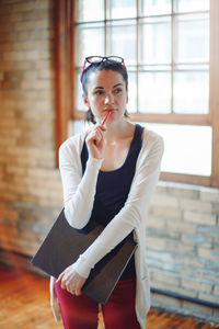 Woman holding book standing against window