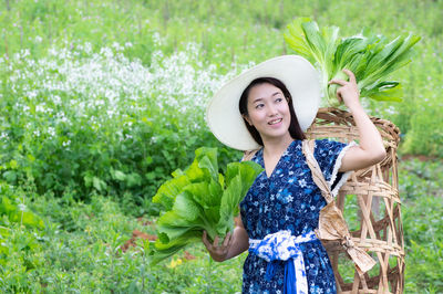 Portrait of a smiling young woman standing against plants