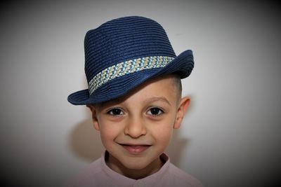 Portrait of cute boy wearing hat against gray background