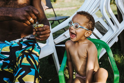 Portrait of shirtless boy holding camera