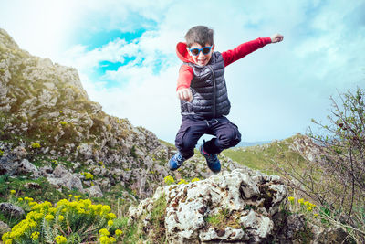 Low angle view of man jumping on rock