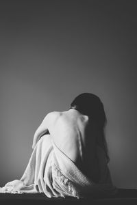 Low angle view of young woman sitting against black background