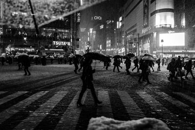 People walking on illuminated street in city at night