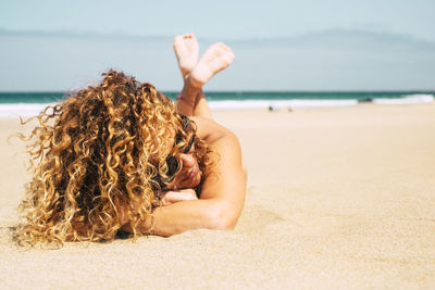 Midsection of woman relaxing on beach