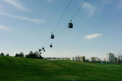 Overhead cable car on field against sky