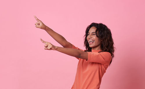 Happy woman standing against pink background