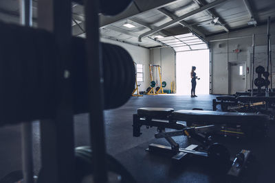 Woman lifting dumbbells while exercising in gym