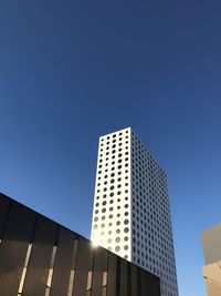 Low angle view of modern building against clear blue sky