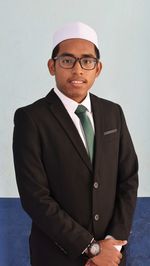 Portrait of a smiling young man standing against wall