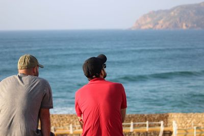 Rear view of people on beach against sky