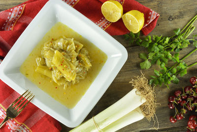 Plate with leek and celery with red hot chili flakes on top and raw ingredients for making it