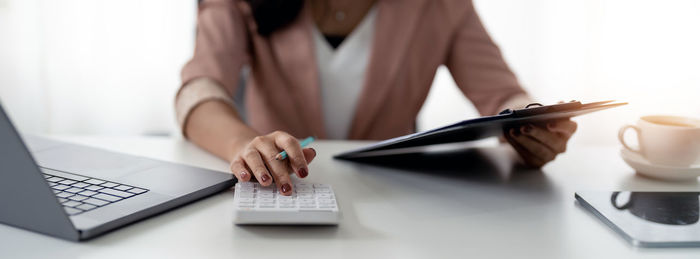 Midsection of businesswoman using laptop on table