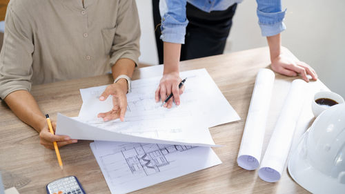 Concept of engineering consulting, two female engineers is checking blueprint of building together.