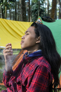 Side view of young woman looking away while standing outdoors