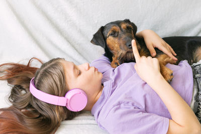 Girl wearing headphones playing with dog