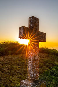 Digital composite image of cross on field against sky during sunset