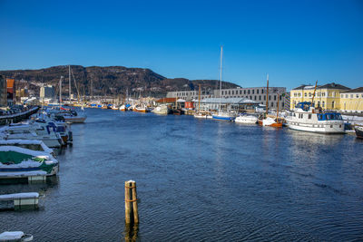 Boats moored at harbor against clear blue sky