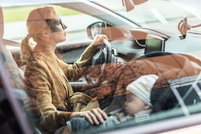 Young woman using mobile phone while sitting in car