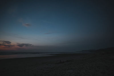 Scenic view of beach against sky at sunset