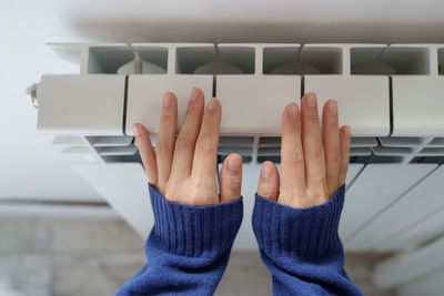 Closeup of woman warming her hands on the heater at home during cold winter days. heating season.